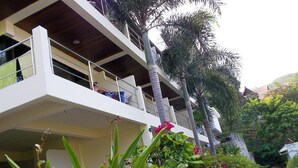 Un edificio a più piani con balconi, immerso nel verde e fiorito.