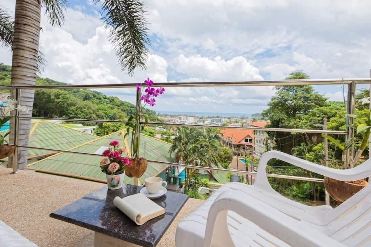 Uma varanda com mesa, cadeiras, um livro e um vaso de flores.