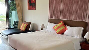 A spacious bedroom with a large bed, a nightstand, a lamp, and a window with curtains.