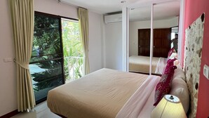 Camera da letto con un letto grande, una lampada da comodino, una finestra con tende e vista sul verde.