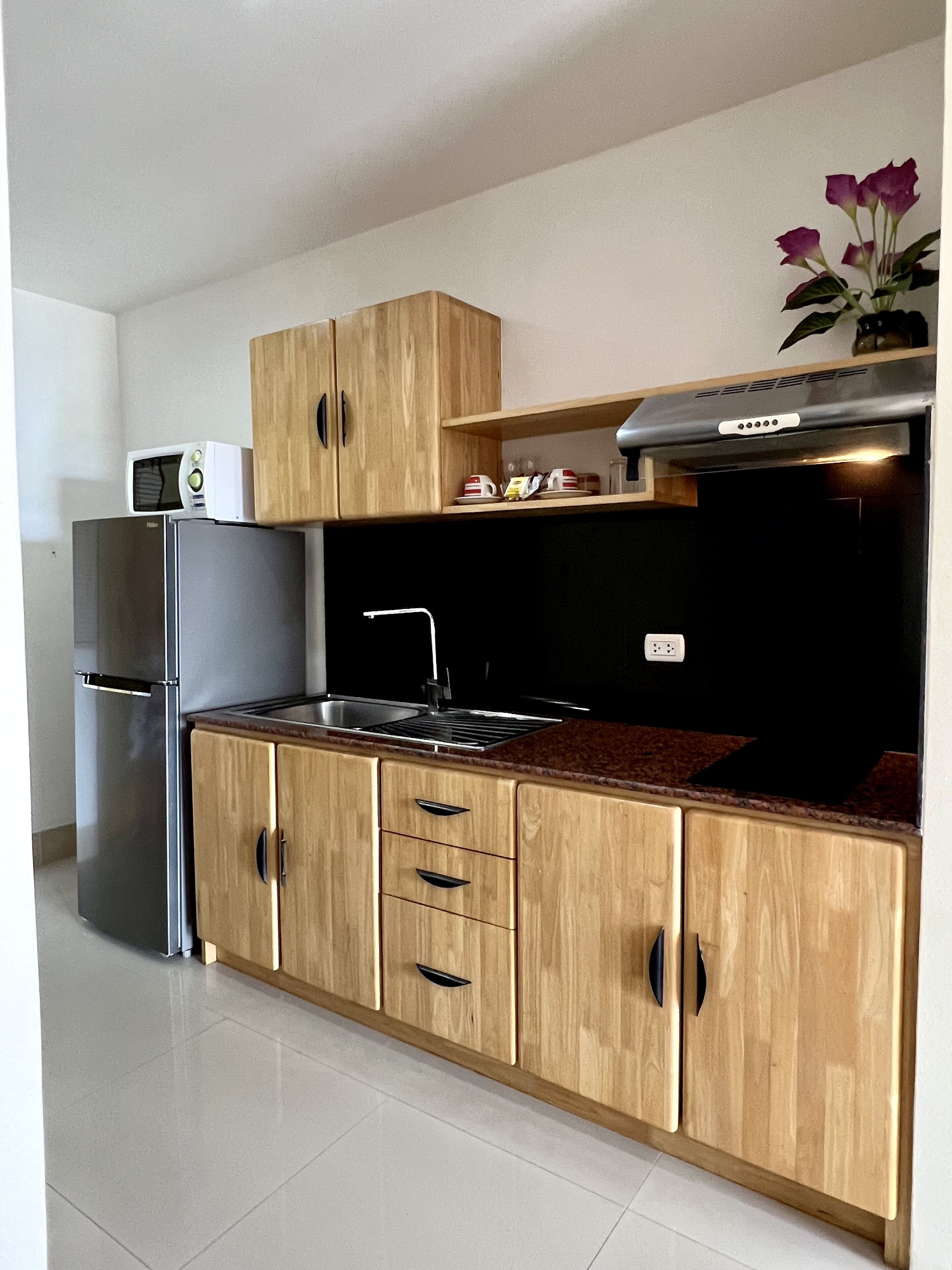 A kitchen with wooden cabinets, a stainless steel refrigerator, a microwave, and a stove.