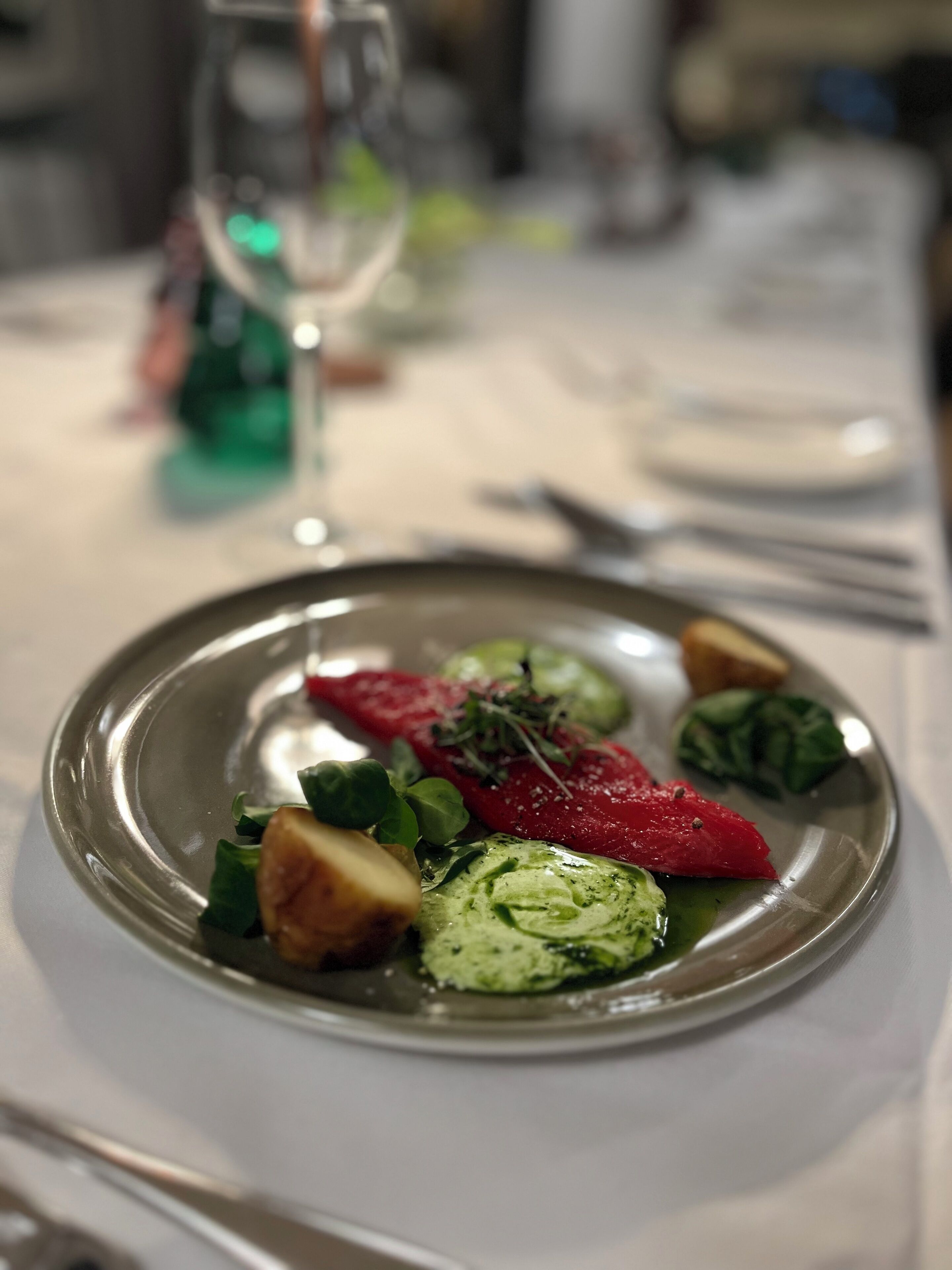 Um prato de comida com diversos vegetais e um copo de água sobre uma mesa.
