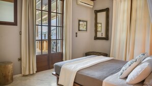 A bedroom with a bed, a large window, a mirror, and a framed picture on the wall. - Faros Residence - Adults Only (Kefalonia)
