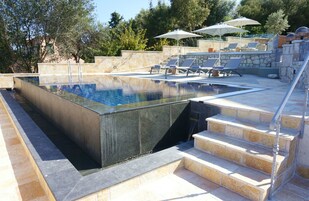 Una piscina al aire libre, sombrillas, sillones reclinables de piscina