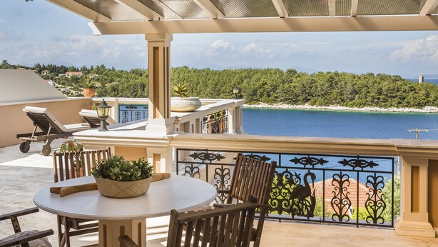 A terrace with a round table, chairs, and a potted plant. - Faros Residence - Adults Only (Kefalonia)