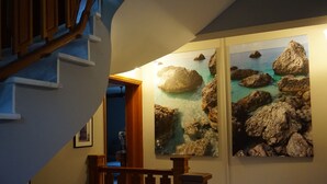 A staircase with wooden railings and a wall with two framed photographs of rocky coastal scenes. - Faros Residence - Adults Only (Kefalonia)