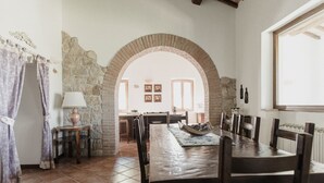Comedor con una larga mesa de madera, un arco de piedra y decoración rústica.