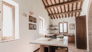 Una cocina con una mesa de madera, una lámpara colgante y una pared de ladrillo.