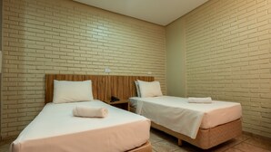 Een hotelkamer met twee enkele bedden, houten hoofdborden en een muur met een baksteenmotief.