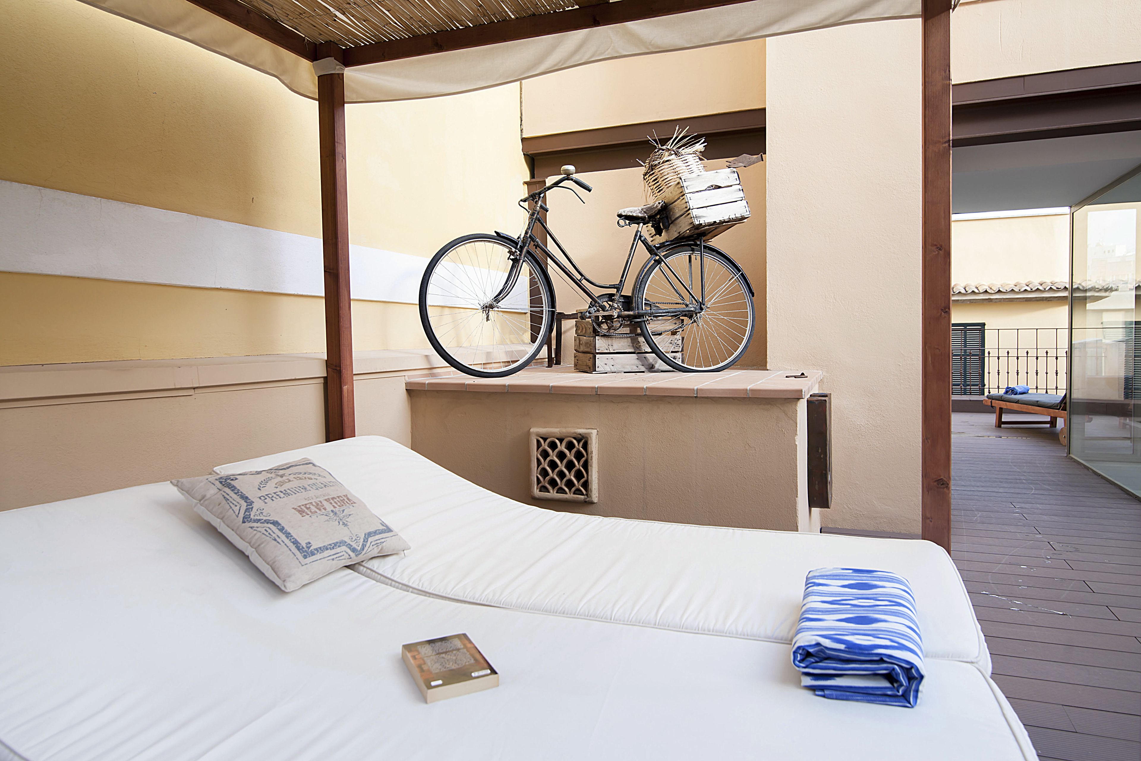 Une chambre d’hôtel avec un lit, un oreiller, un livre et un vélo avec un panier sur le balcon.
