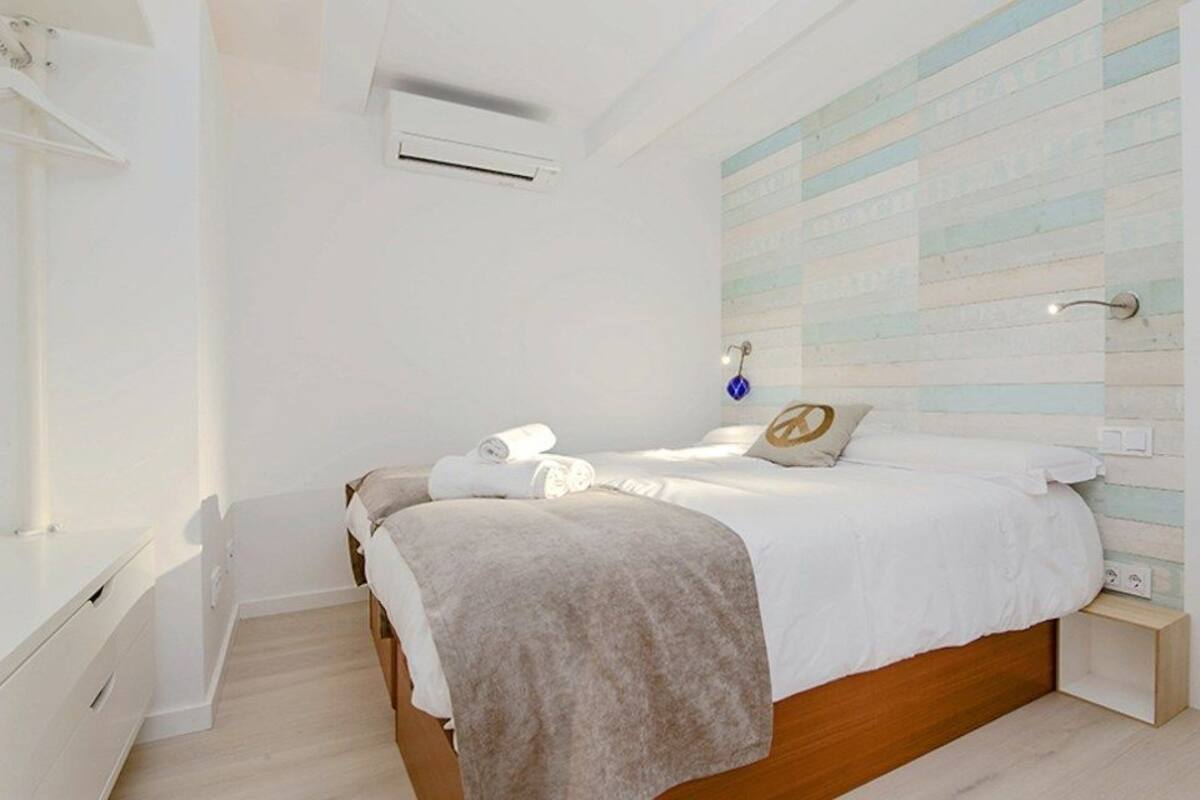Un dormitorio moderno con una cama de madera, ropa de cama blanca y un diseño de pared a rayas.