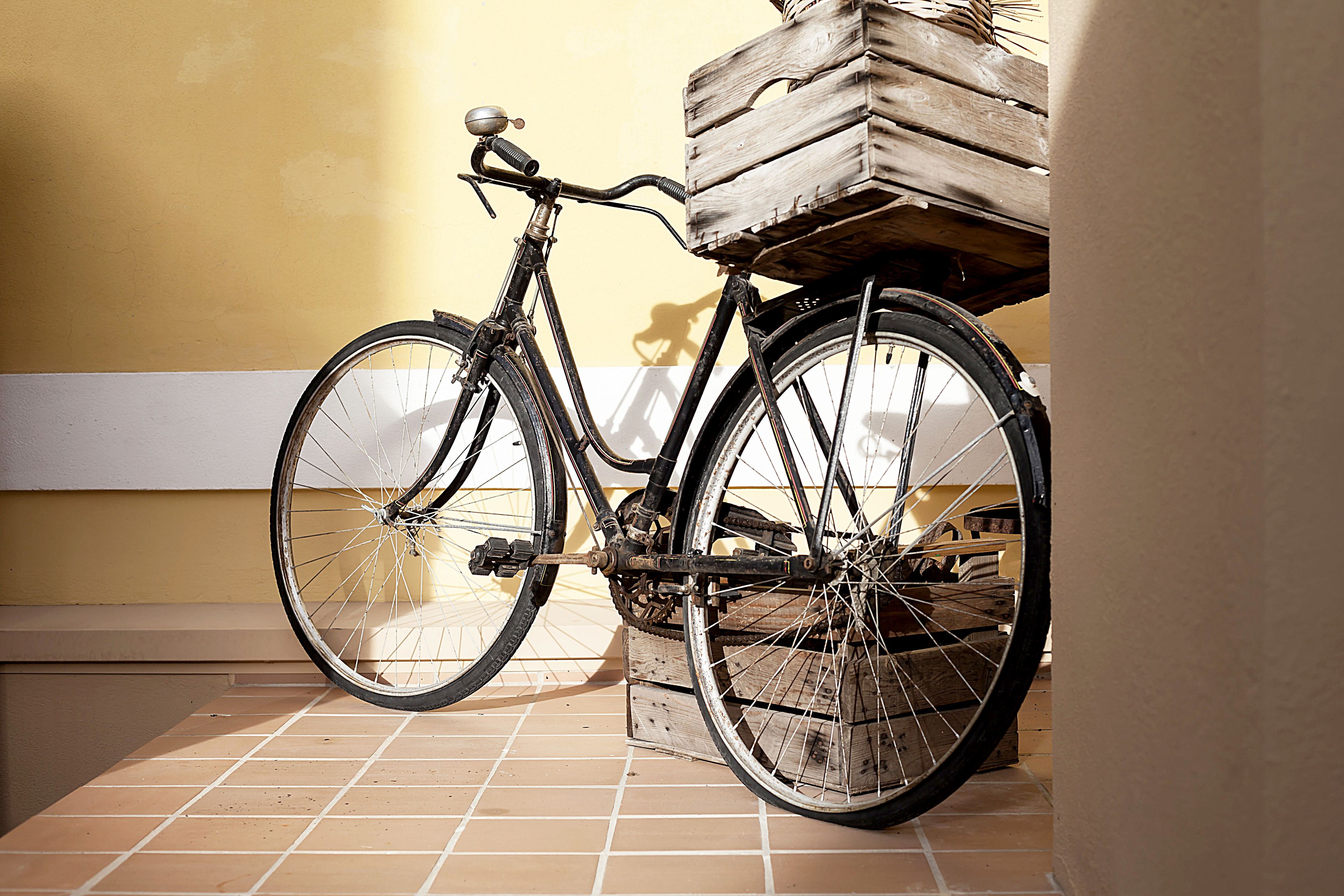 A bicycle with a wooden crate on the back parked against a wall.