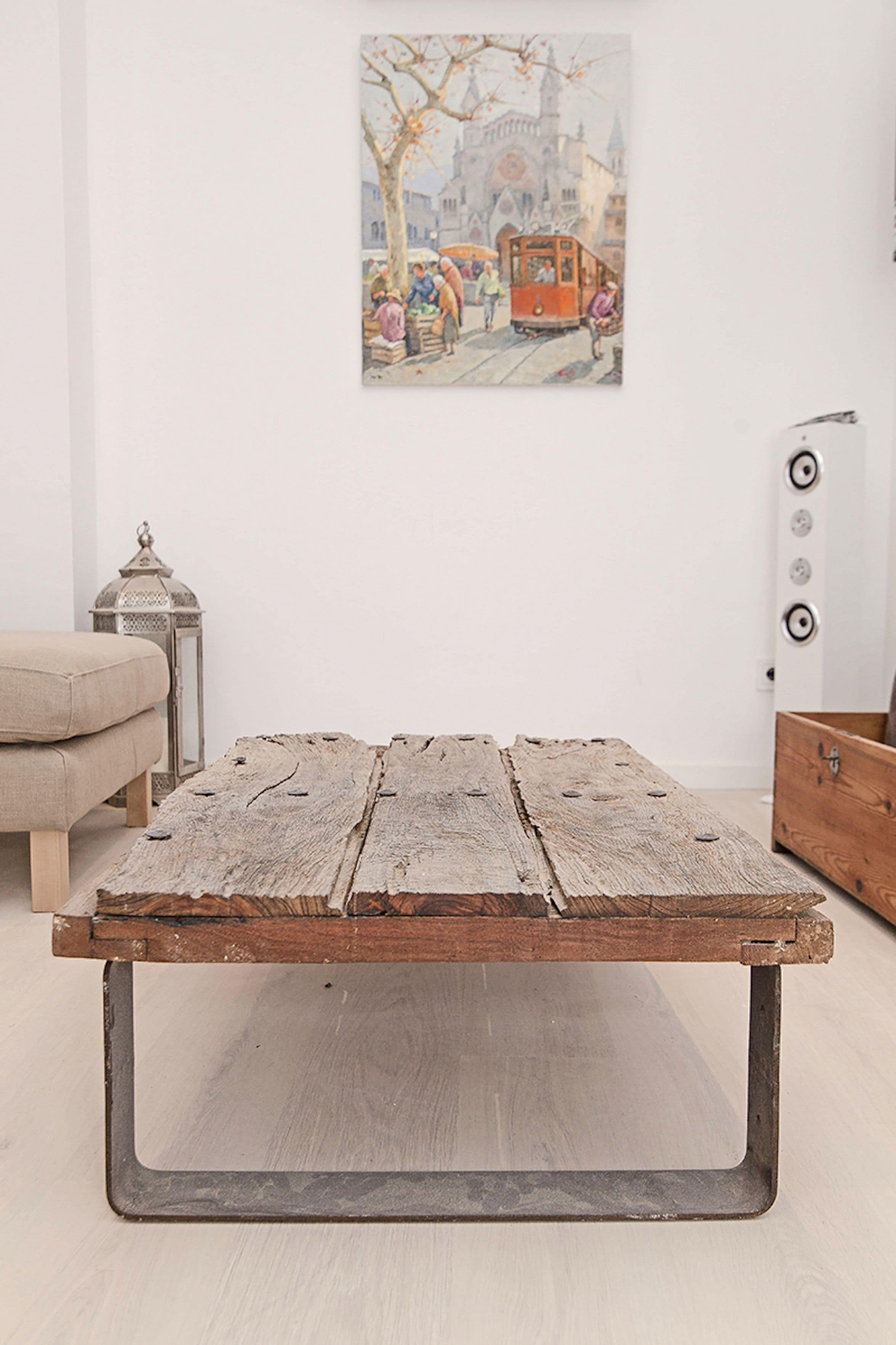 A rustic wooden table with metal legs, a beige sofa, a small lantern, and a wall-mounted radiator.