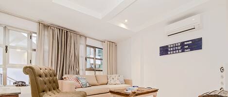 A living room with a sofa, a leather armchair, a wooden coffee table, and a chest of drawers.