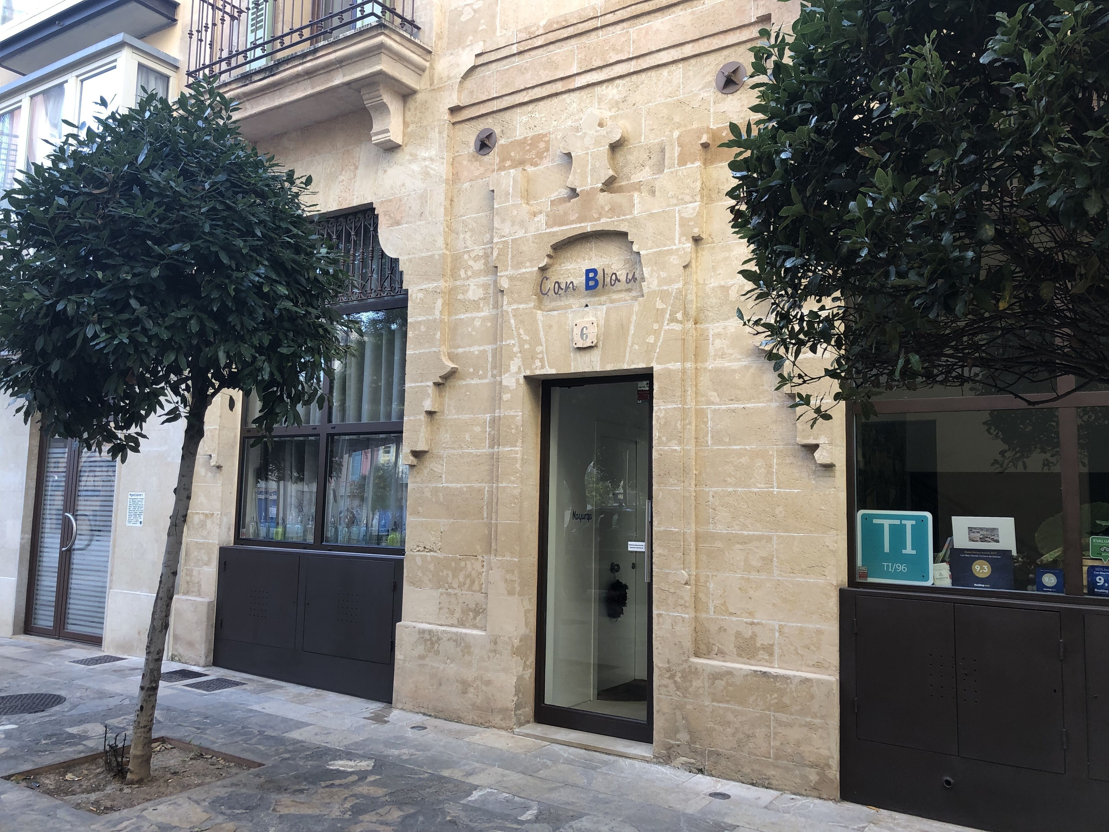 Un edifici amb façana de pedra, una porta amb un panell de vidre i un senyal que indica una zona d'aparcament TI/96.
