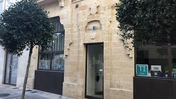 Un edifici amb façana de pedra, una porta amb un panell de vidre i un senyal que indica una zona d'aparcament TI/96.