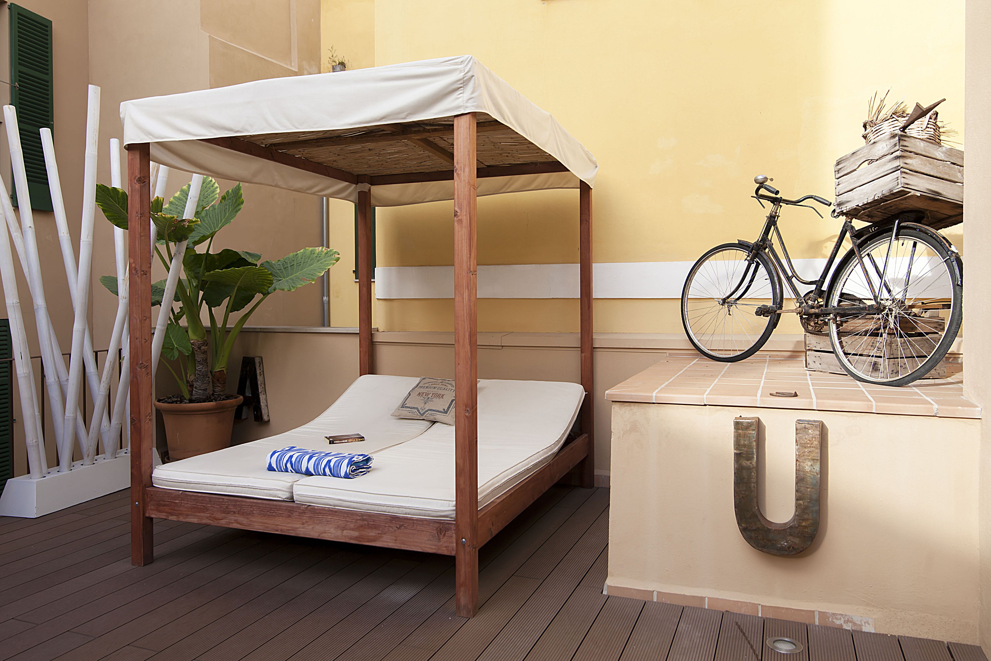 A bed with a canopy, a bicycle, and a letter 'U' on a wall.