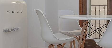 A modern room with a white table and chairs, a white wall, and a door labeled "SMEG".