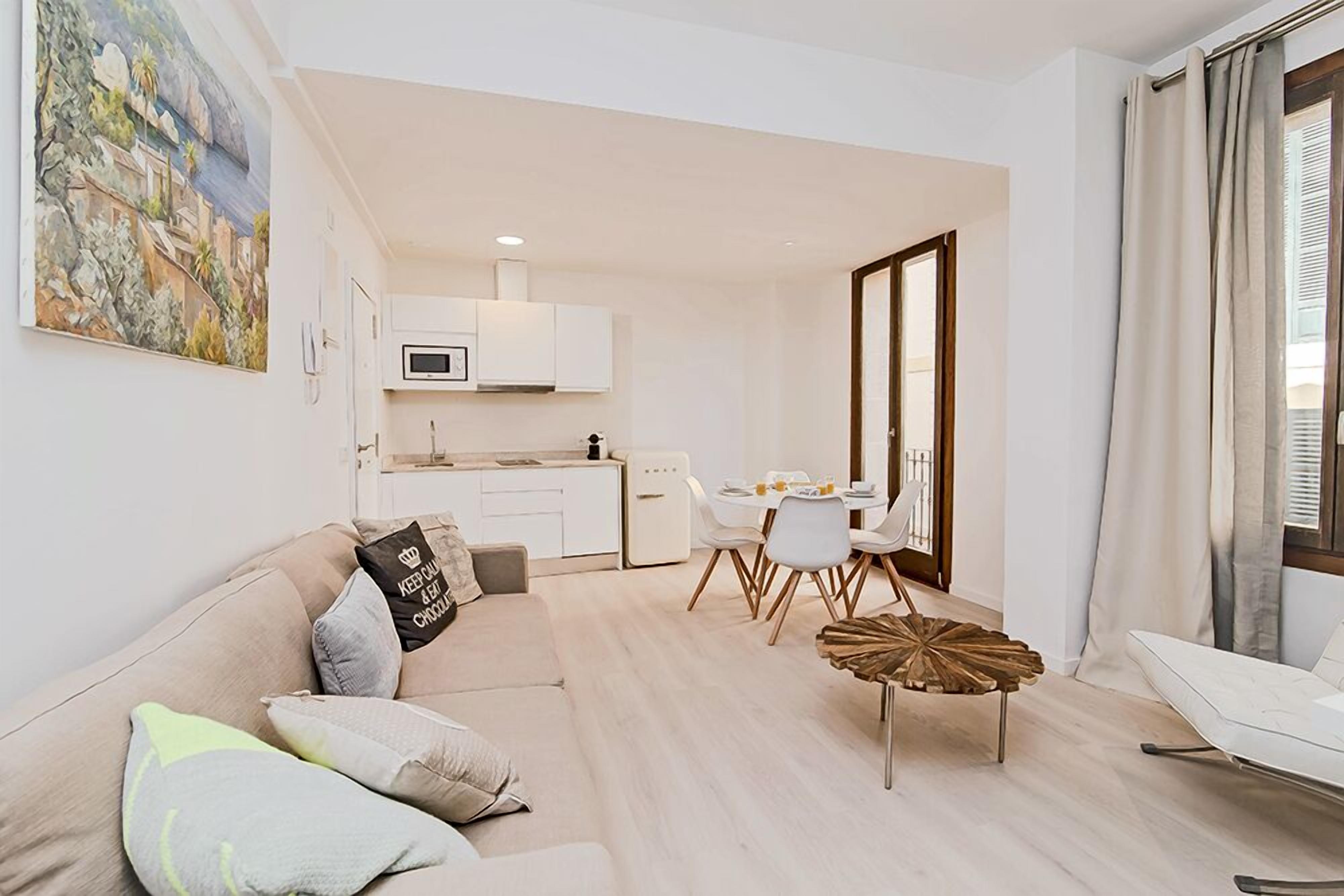 Una sala moderna con un sofá, una mesa de comedor y una cocina al fondo.
