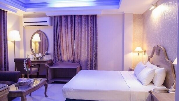 Quarto de hotel com cama, secretária, cadeira e luminária.