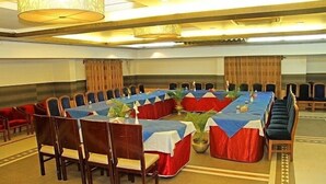 Un salón de conferencias con una mesa larga, sillas y una araña.