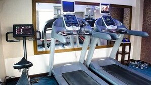 Un gimnasio con cintas de correr, una bicicleta estática y una máquina de remo.