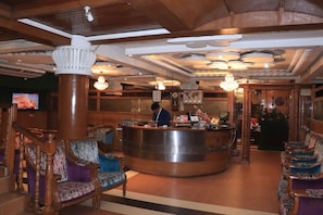 Una hall con una reception, arredi in legno e un lampadario.