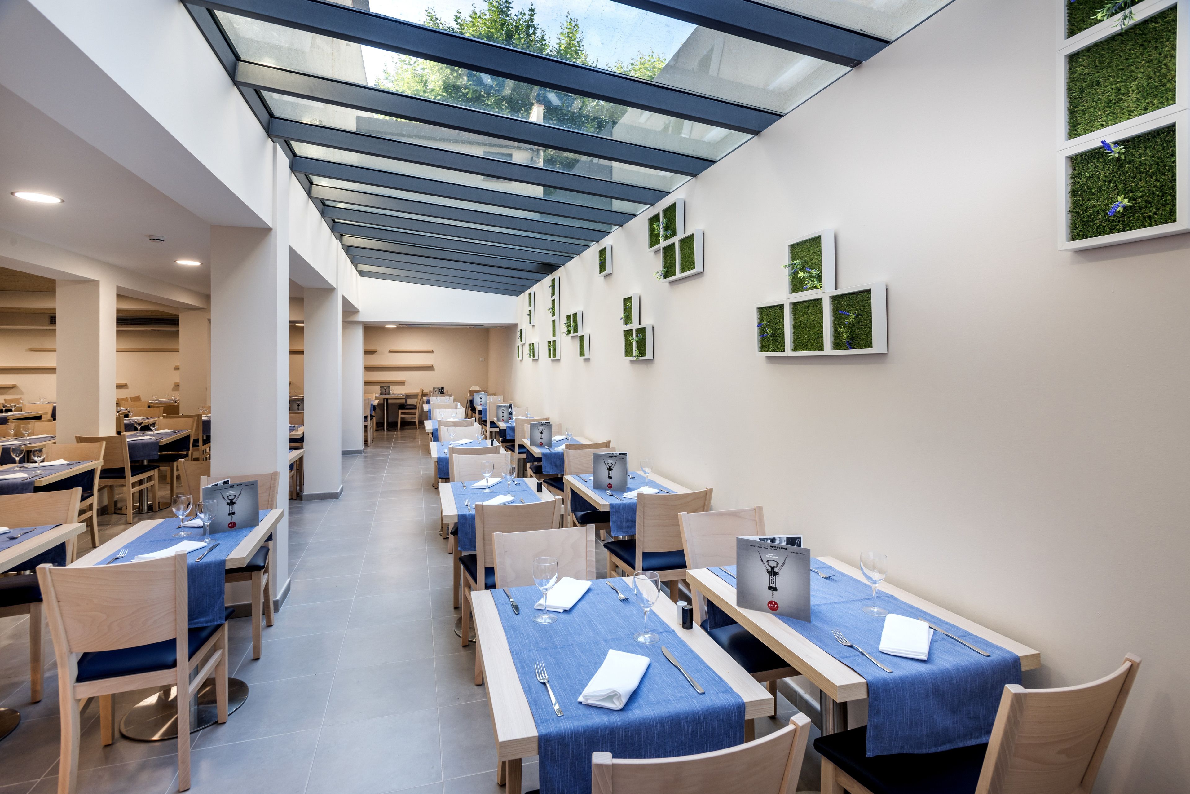 A modern dining area with glass ceiling, neatly arranged tables, and chairs.
