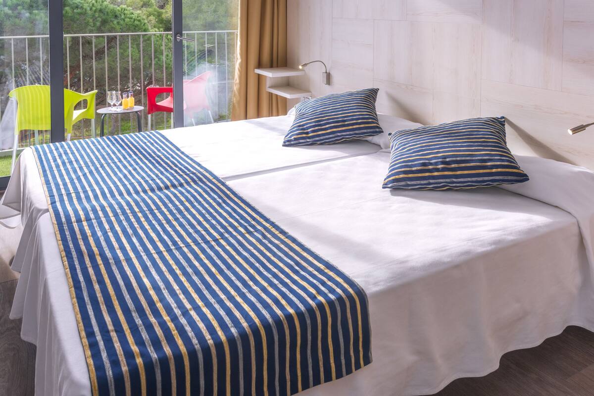 Una cama doble con ropa de cama a rayas, una mesita de noche y una silla.