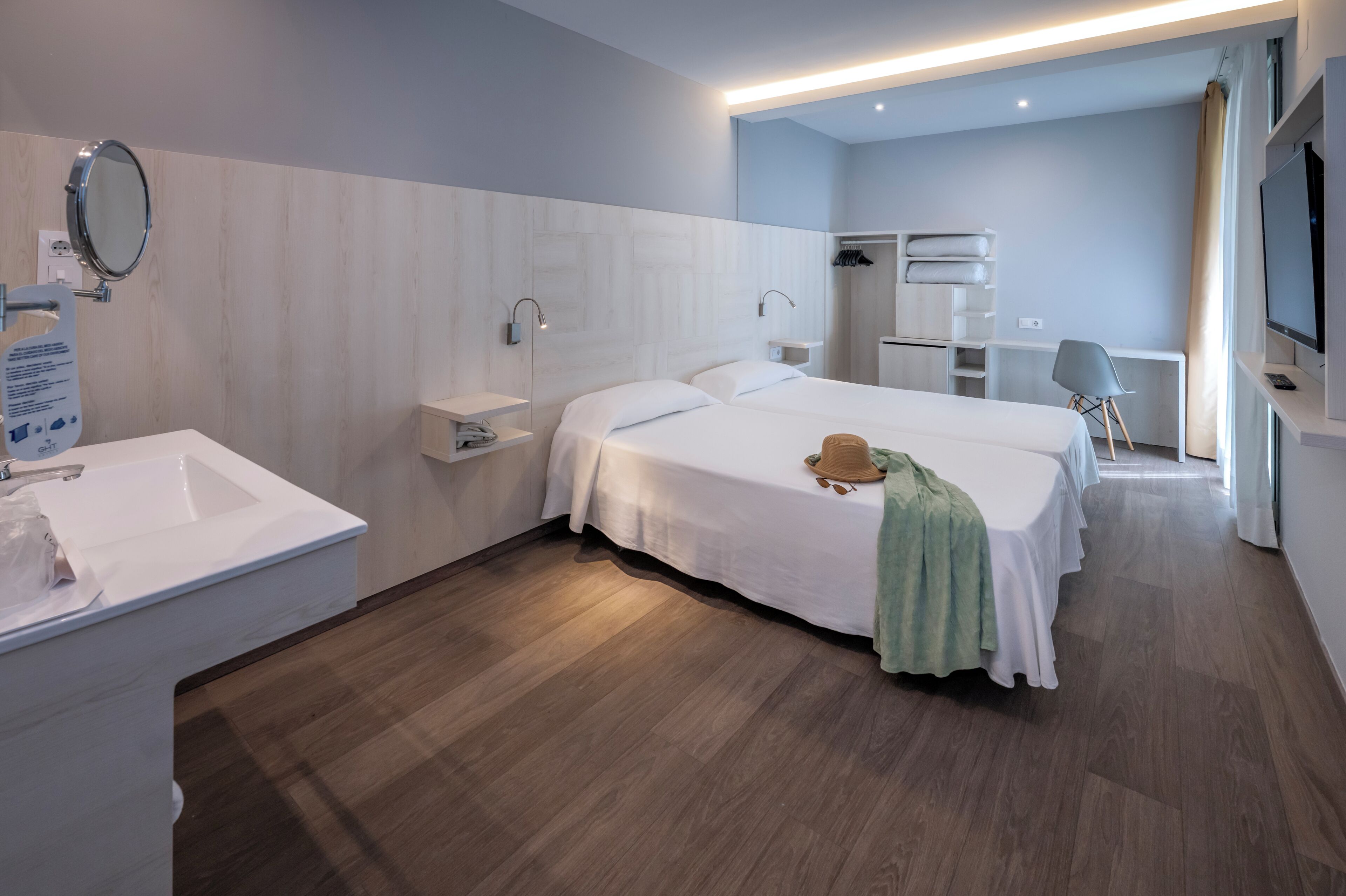 Habitación de hotel con una cama grande, una mesita de noche, un espejo, un armario, un televisor y un área de baño.