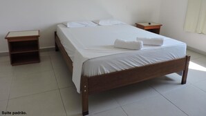 A single-bed room with a wooden frame, white bedding, two nightstands, and a plain white wall. - Consulado Praia Hotel (Guarujá)