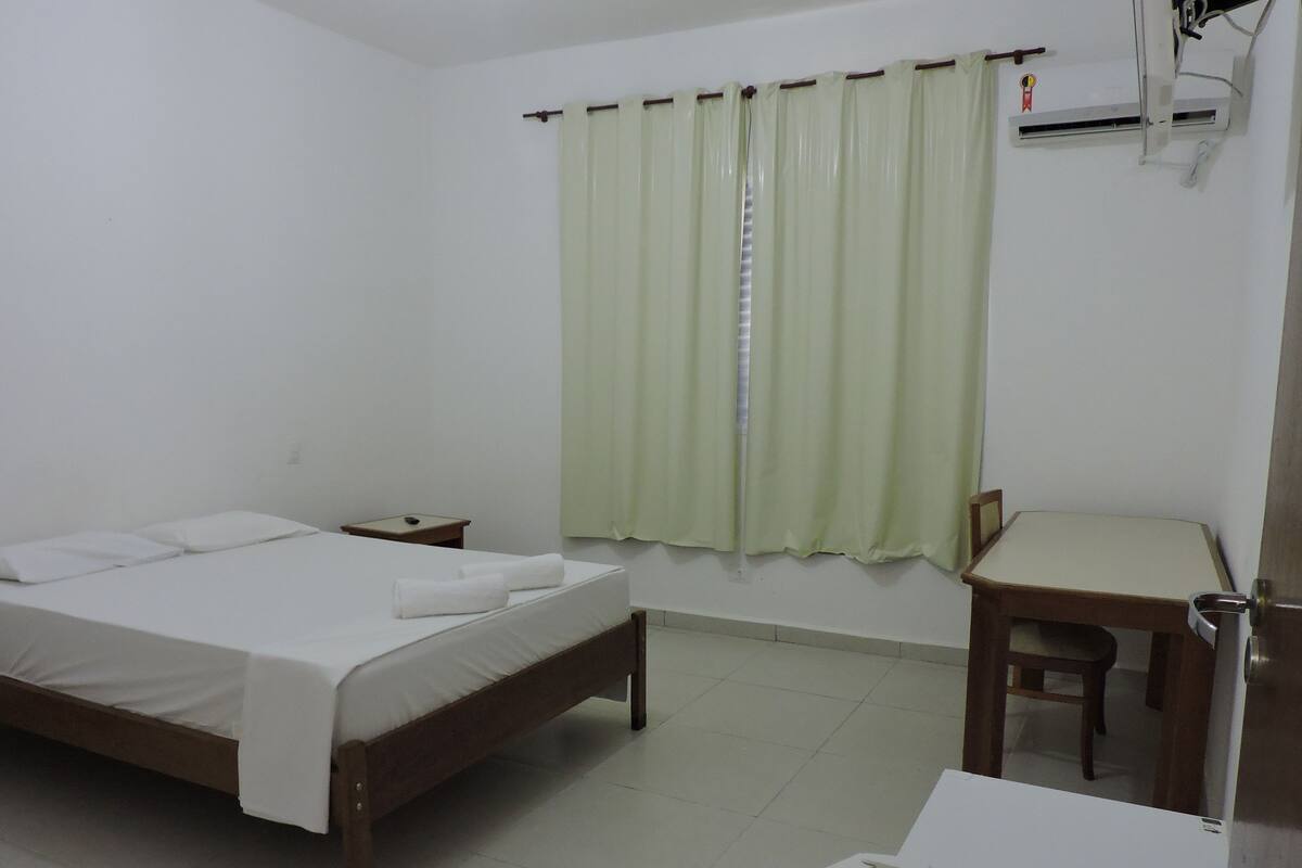 A simple, clean room with a bed, a desk, and a chair.