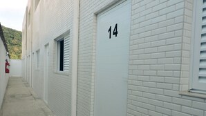 A white brick building with a number 14 garage door. - Consulado Praia Hotel (Guarujá)