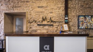 Una recepción con un fondo de pared de piedra, una obra de arte enmarcada y un letrero que dice 'alda hotels'.