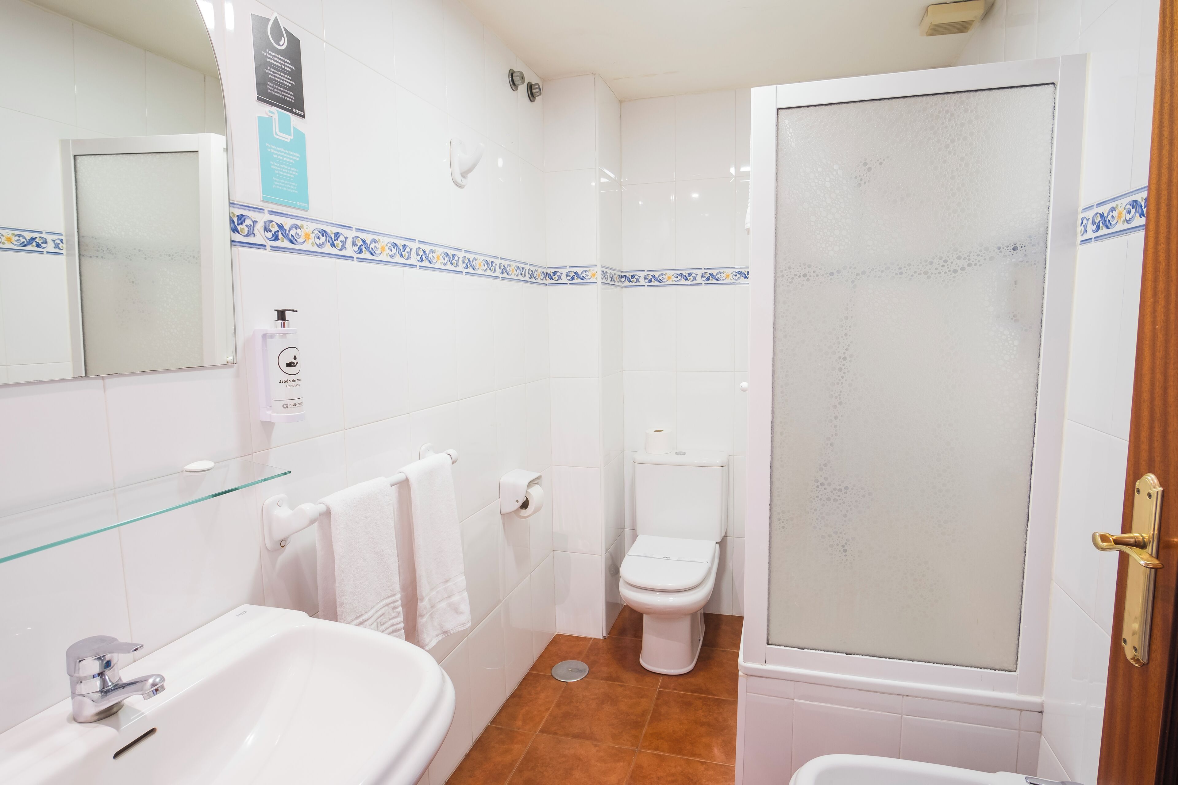 Un baño con lavabo, inodoro y ducha con mampara de vidrio.