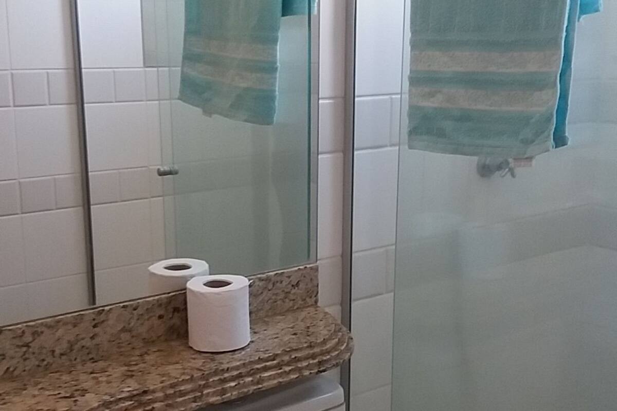 Une salle de bain comprenant des toilettes, un lavabo avec un plan de travail en granit, un miroir et une douche avec une porte en verre.