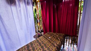 Quarto com cama, cortinas e chão de madeira.