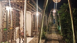 A pathway lined with decorative metal railings and illuminated by hanging lights, leading to a building with traditional architecture. - FunkyPlace (Buleleng)