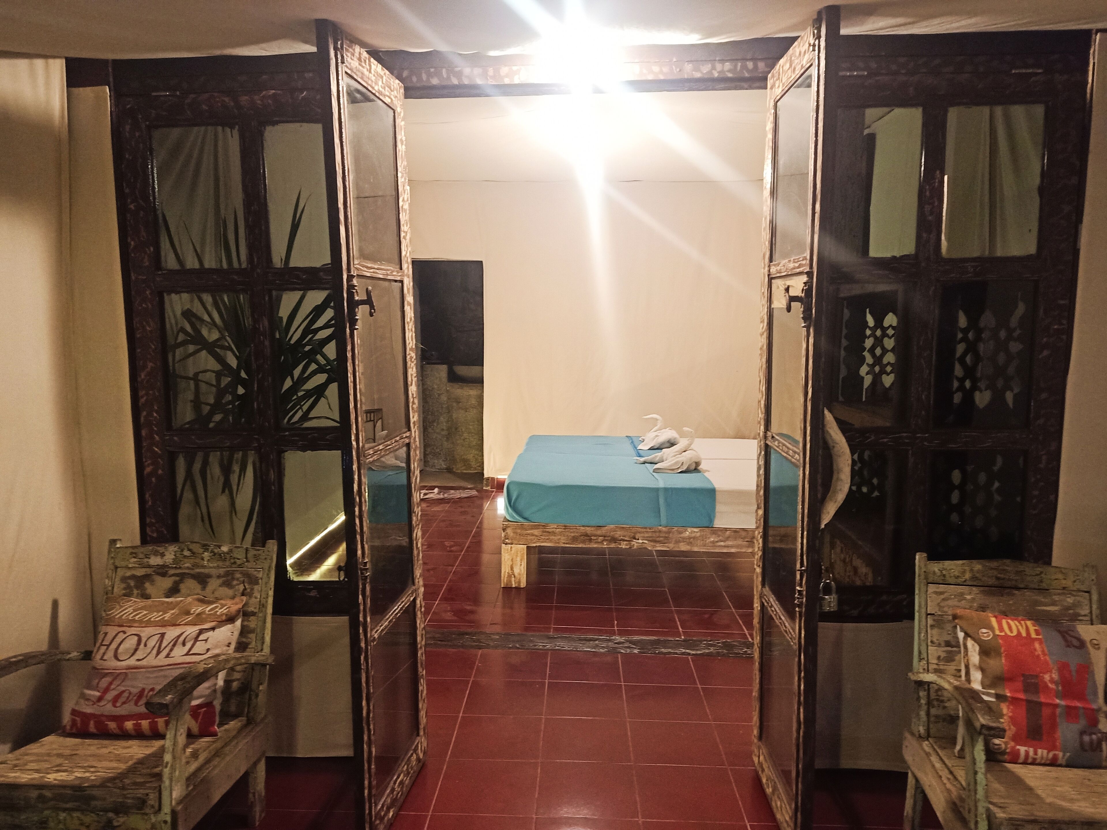 Una habitació amb llit, cadira i mirall.