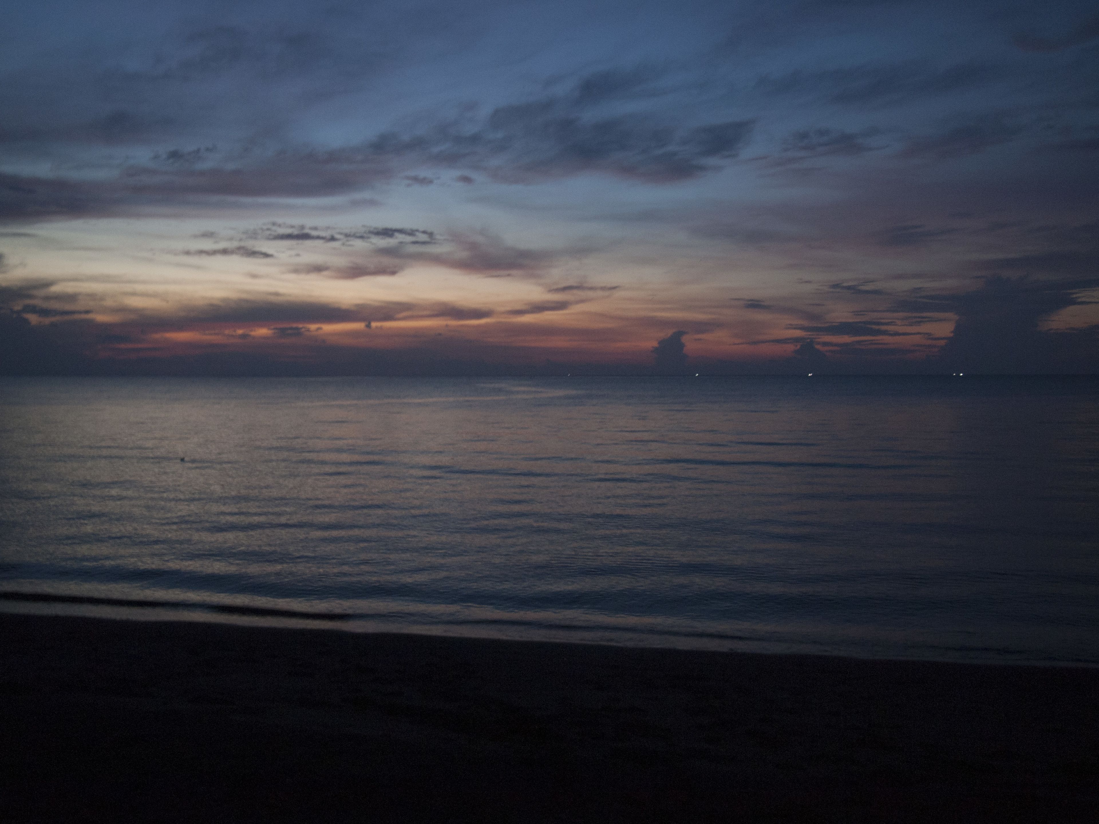 Una spiaggia al crepuscolo con mare calmo e cielo nuvoloso.