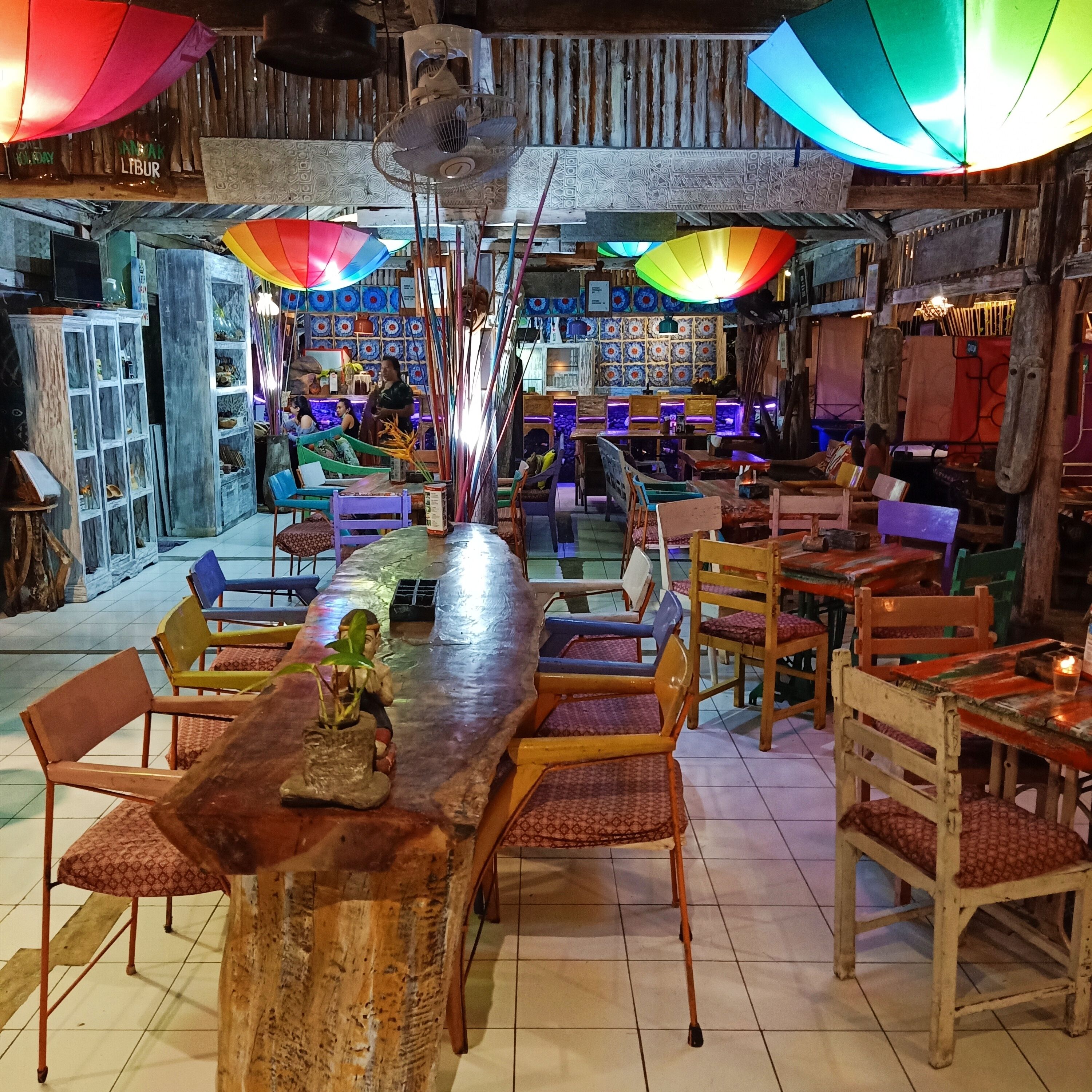 Um espaço de bar rústico, com móveis de madeira e coloridas ombrelhas.