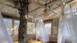 A room with a thatched roof, wooden floors, and two beds with mosquito nets. - FunkyPlace (Buleleng)