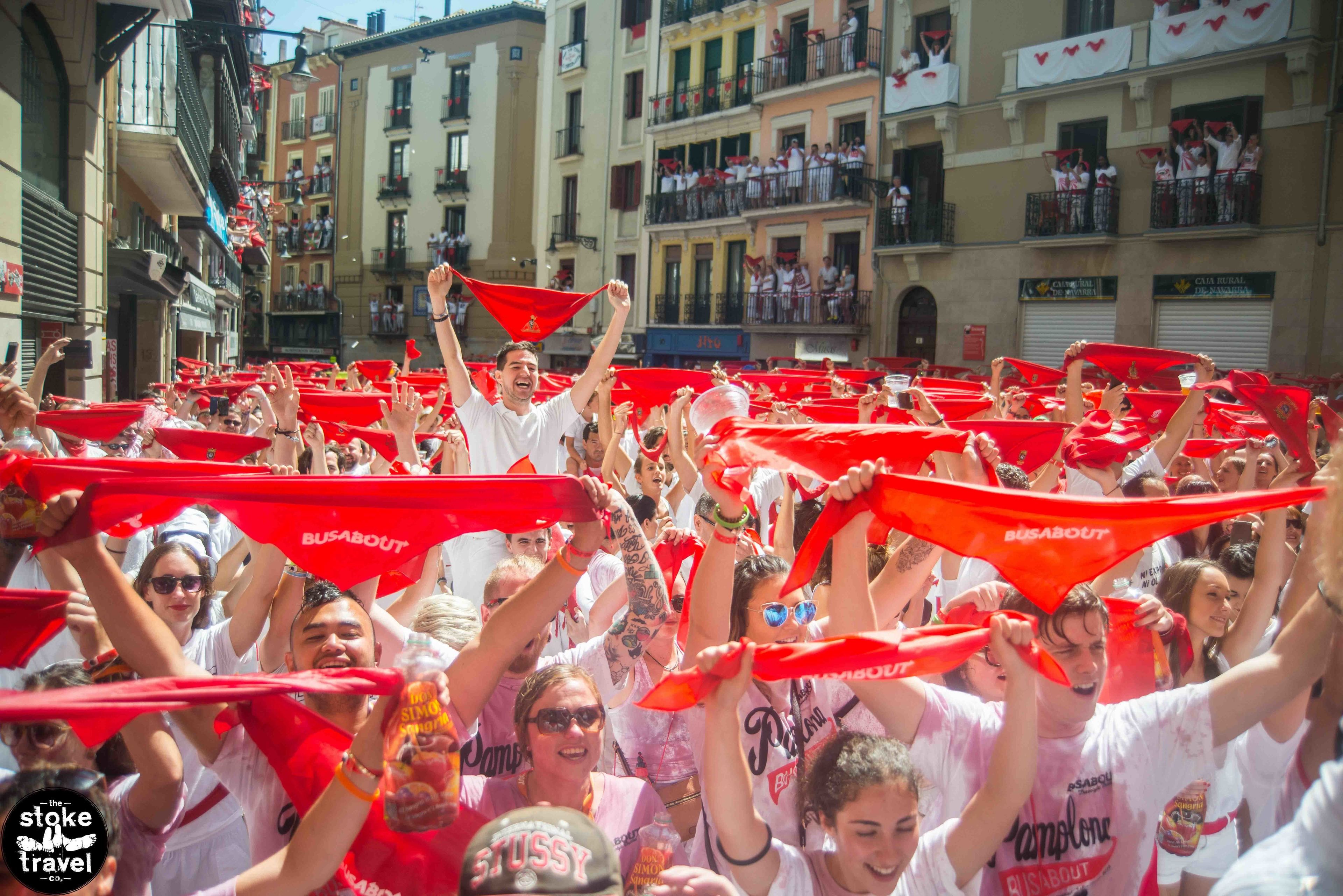 A group of people holding red flags in a crowded street.
