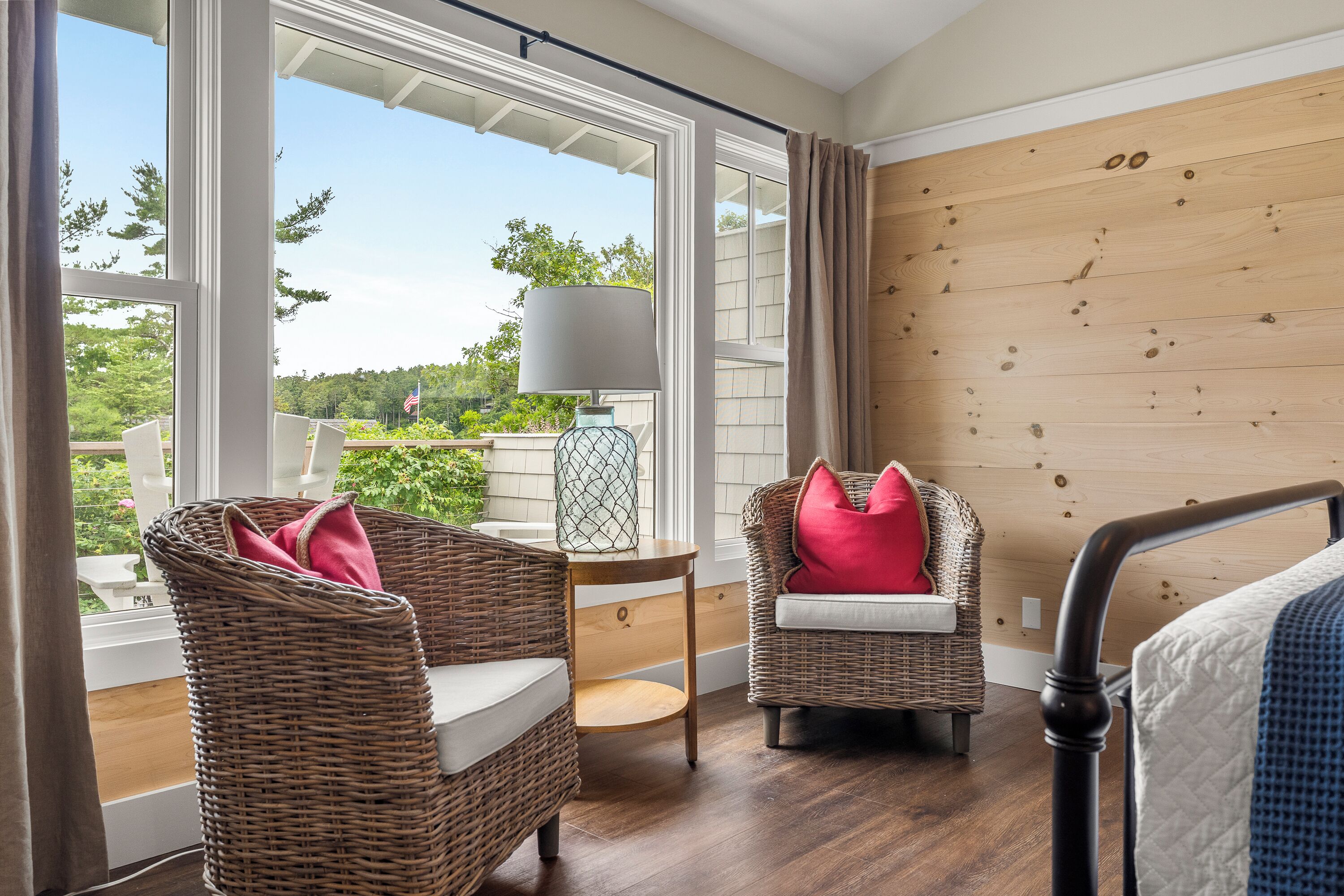 Habitación con muebles de mimbre, una lámpara y vistas a zonas verdes.