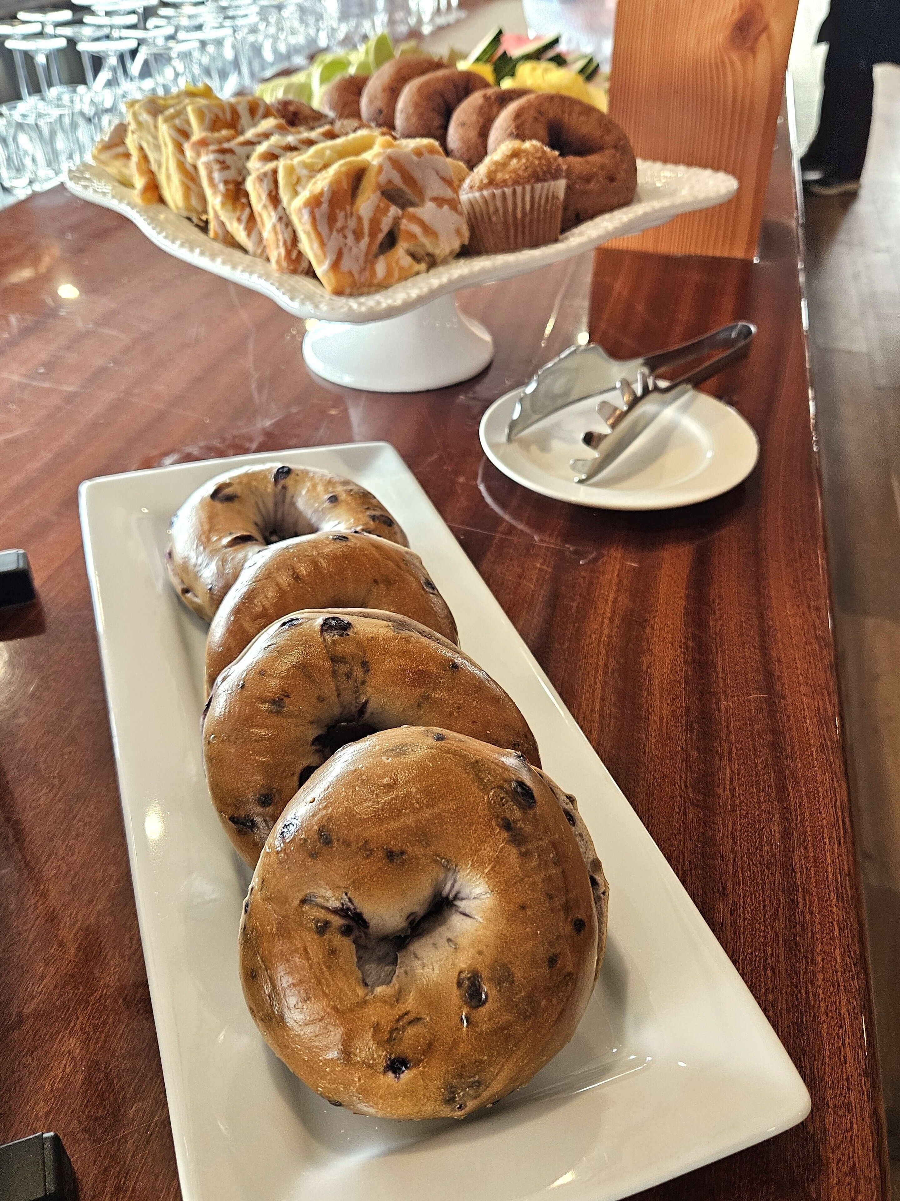 Una mesa de buffet con diversos productos de panadería, como bagels y muffins.