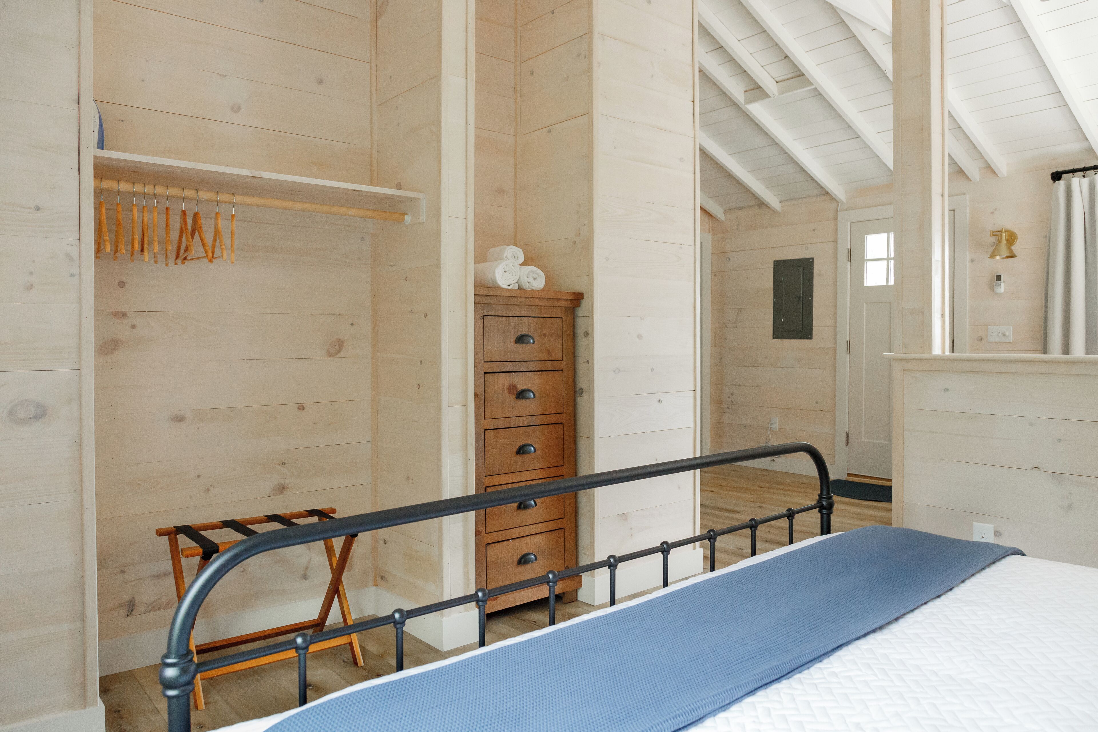A bedroom with a bed, wooden wardrobe, and a dresser.