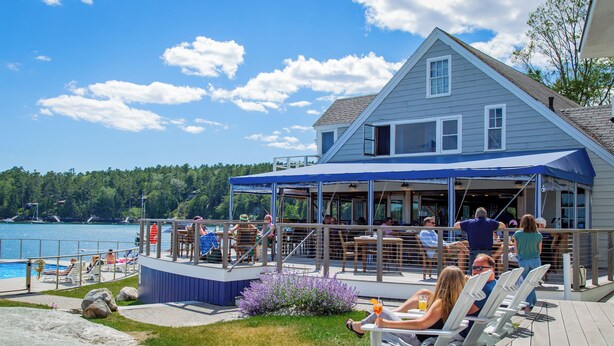 A lakeside deck with seating and a covered area, overlooking a body of water and a forested area. - Linekin Bay Resort (Boothbay Harbor)