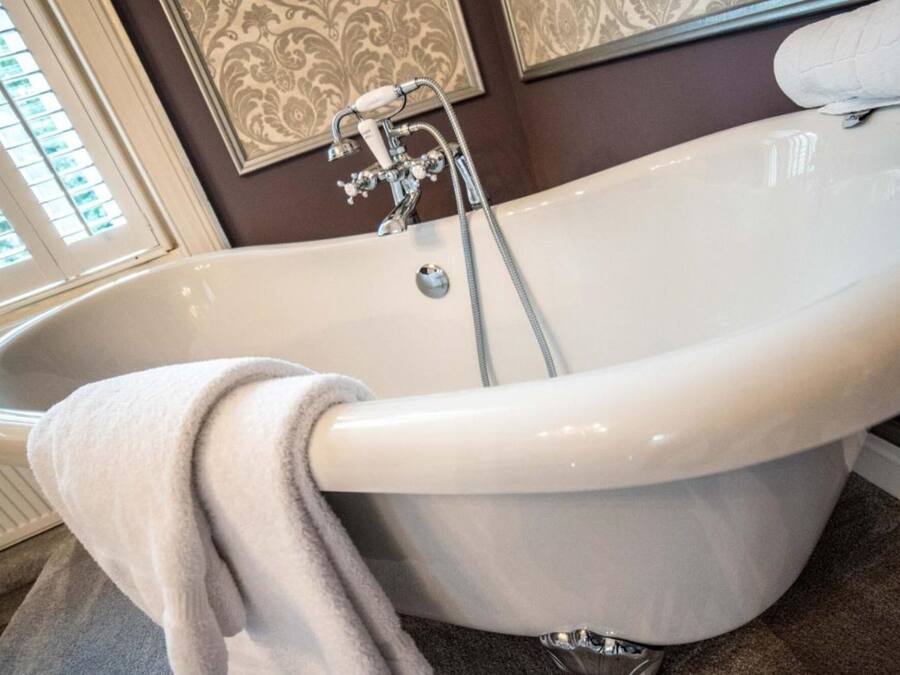 A freestanding bathtub with a shower head and a towel draped over it.