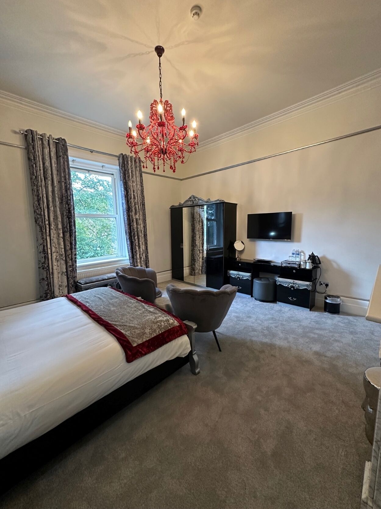 Ein Schlafzimmer mit einem großen Bett, einer Chandelüster, einem Fernseher und einem Kleiderschrank.