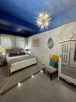 Een slaapkamer met een bed, een stoel, een kledingkast en een plafondlamp.
